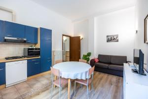 米蘭的住宿－Stazione Centrale-Repubblica Appartamento in centro con WIFI，厨房以及带白色桌子和蓝色橱柜的用餐室。