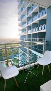 a balcony with two chairs and a large building at LeisureStay Studio @ Azure North in San Fernando