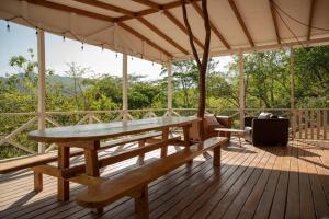 a wooden deck with a table and benches on it at Blue Container La Paillote in Paquera