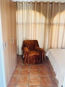 a brown chair sitting in the corner of a bedroom at The House in Casas Devesa