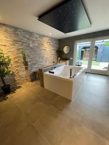 een grote badkamer met een bad en een stenen muur bij Bed & Wellness Chinel Luxe vakantiehuis met Sauna's en Bubbelbad in Sint Annaland