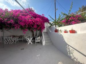 a balcony with pink flowers and tables and chairs at Kefia 1 in Mesaria