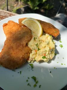 a plate of food with fish and potato salad and a lemon wedge at FeWo im Gasthof Forsthaus in Marktredwitz