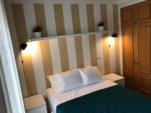 um quarto com uma cama com lençóis brancos e almofadas em Gemini Apartment by AM no Funchal