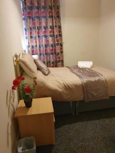 a small bedroom with a bed and a table with flowers at Blackpool Central Apartments 2 Bedroom FF in Blackpool