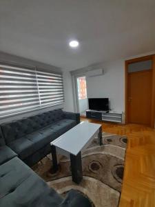 ein Wohnzimmer mit einem Sofa und einem Tisch in der Unterkunft Stan na dan Pepi Lukavica, Sarajevo in Donje Mladice