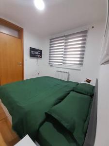 ein grünes Bett in einem weißen Zimmer mit Fenster in der Unterkunft Stan na dan Pepi Lukavica, Sarajevo in Donje Mladice