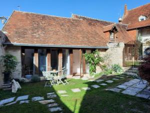 una vecchia casa con tavolo e sedie nel cortile di Gîte de charme - La Cure Pontlevoy a Pontlevoy