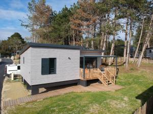 a tiny house with a porch and a deck at Cottage Jullouville récent l'Edune résidence vacances - plage 150 m -piscine - Wifi in Jullouville-les-Pins