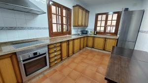 una cocina con armarios de madera y electrodomésticos de acero inoxidable en La casa de Pi, en Torrecaballeros