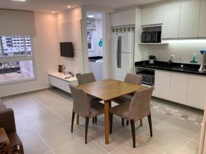 a kitchen with a wooden table and chairs in it at Apartamento a 100m da beira-mar in Capão da Canoa