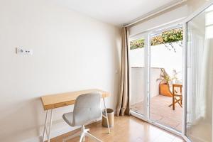 una scrivania e una sedia in una stanza con porta scorrevole in vetro di Oasis Urbano Ciudad Expo a Mairena del Aljarafe