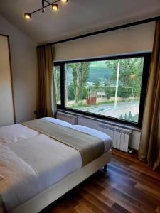 a bedroom with a bed and a large window at Dili Dream Villa Resort in Dilijan
