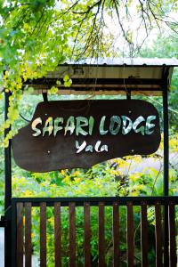 un letrero para un lodge saar valencia colgando sobre una valla en Safari Lodge Yala, en Kataragama