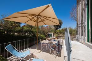 patio con tavolo, sedie e ombrellone di Villa Tozzoli House a Sorrento