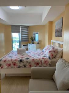 a bedroom with a bed and a couch at Two Bedroom - The Bali Corner at Azure North in San Fernando