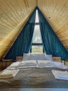 a bed in a room with a large window at Wildwood Kazbegi in Stepantsminda