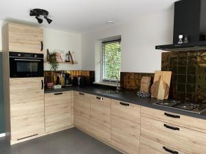 a kitchen with wooden cabinets and black counter tops at Luxe Vakantiehuis Vosje op de Veluwe Nunspeet in Nunspeet