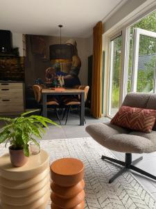 een woonkamer met een tafel en een stoel bij Luxe Vakantiehuis Vosje op de Veluwe Nunspeet in Nunspeet