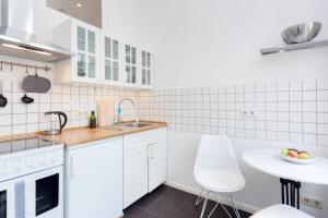 eine Küche mit weißen Schränken, einer Spüle und einem Tisch in der Unterkunft Brüsseler Straße 39 in Berlin