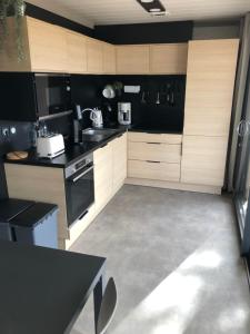 a kitchen with wooden cabinets and black counters at Cottage Jullouville récent l'Edune résidence vacances - plage 150 m -piscine in Jullouville-les-Pins