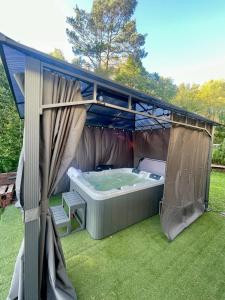 una bañera de hidromasaje bajo un dosel en un patio en Osada Skoczkowo domki z kominkami, jacuzzi, balią i sauną nad jeziorem en Podiazy