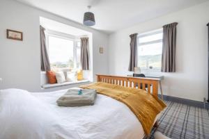 a bedroom with a large white bed and two windows at Cosy Hygge/ Scottish themed home by Loch Ness in Fort Augustus