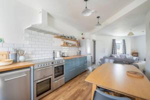 a kitchen with blue cabinets and a table in it at Cosy Hygge/ Scottish themed home by Loch Ness in Fort Augustus