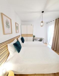 1 dormitorio blanco con 1 cama blanca grande con almohadas azules en BuenaVista Gigantes Marina - Room with Private Bathroom en Acantilado de los Gigantes