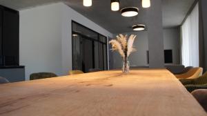- une longue table avec un vase de plumes dans la chambre dans l'établissement Marina Maisonette Seeblick mit Pool und Sauna, à Bad Saarow