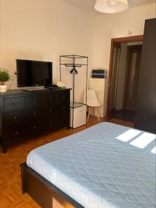 ein Schlafzimmer mit einem Bett und einer Kommode mit Fernseher in der Unterkunft Vito's Room in Cormano