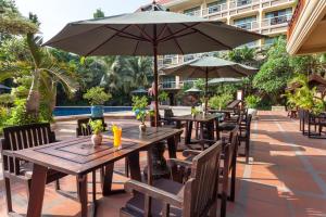 an outdoor patio with tables and chairs and an umbrella at Prince Angkor Hotel & Spa in Siem Reap