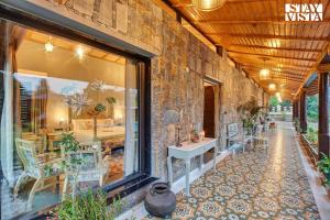 un bâtiment avec un mur en pierre et une pièce avec des tables et des chaises dans l'établissement StayVista at The Earthen Boutique with Spacious Pool, Terrace, Lawn & Games, à Udaipur