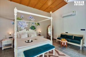 une chambre avec un lit blanc et un canapé dans l'établissement StayVista at The Earthen Boutique with Spacious Pool, Terrace, Lawn & Games, à Udaipur 26 autres photos