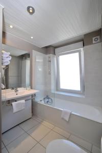 a bathroom with a tub and a sink and a toilet at The Originals Access, Hôtel Arum, Remiremont (Inter-Hotel) in Remiremont