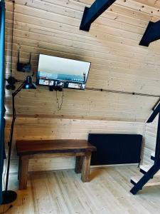 a room with a wooden wall with a bench and a tv at Wildwood Kazbegi in Stepantsminda