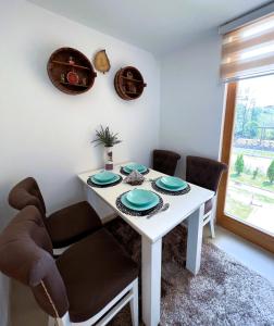 uma sala de jantar com uma mesa branca e cadeiras em Apartman Zen em Zlatibor