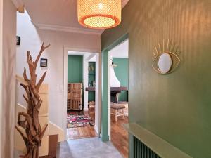 un pasillo de una casa con paredes verdes y espejo en Bonheur dans le Finistère cosy jardin 2-8 pers en Névez