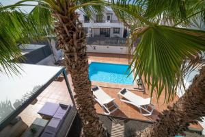 a swimming pool with two chairs and a palm tree at Villa Ariana Playa Blanca in Playa Blanca