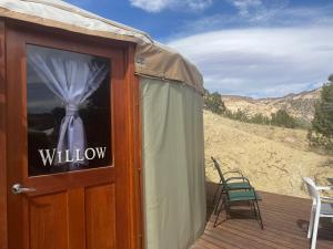 a yurt with a door and a chair on a deck at Escalante Yurts - Luxury Lodging in Escalante