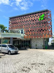 un edificio con un coche aparcado delante de él en T HOTEL KUALANAMU, en Lubukpakam