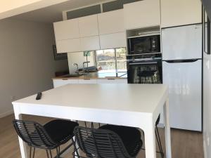 a kitchen with a white counter and chairs at Belles Vues in Saint-Denis