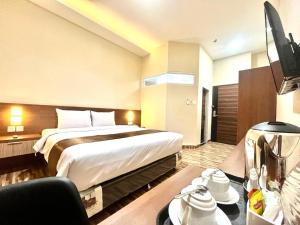 a hotel room with a bed and a television at T HOTEL KUALANAMU in Lubukpakam