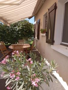 - une terrasse avec une table, des chaises et des fleurs dans l'établissement le gite de margot, à Beyssac