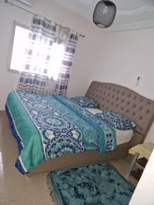 um quarto com uma cama com um cobertor azul e verde em Residence Les Bourgeois appartementen. em Iaundé