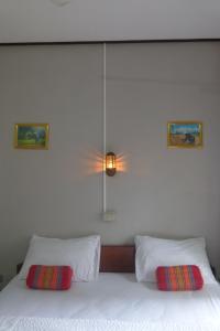 ein Schlafzimmer mit einem weißen Bett mit zwei Kissen in der Unterkunft Khamphouy Guesthouse in Champasak