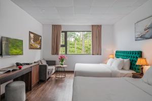 une chambre d'hôtel avec deux lits et un canapé dans l'établissement TTR Moonstone Apart Hotel, à Đà Lạt
