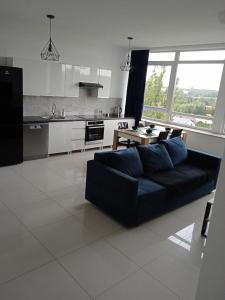 a living room with a black couch and a kitchen at Apartament Panorama Kalisz Złota 71 in Kalisz