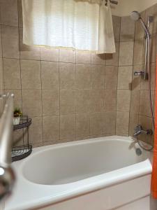 a bath tub in a bathroom with a shower at Sweet Home Grenada Caribbean in Lance aux Épines