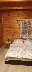 um quarto com uma cama e uma parede de madeira em Dom na Kresach Grzybowszczyzna 